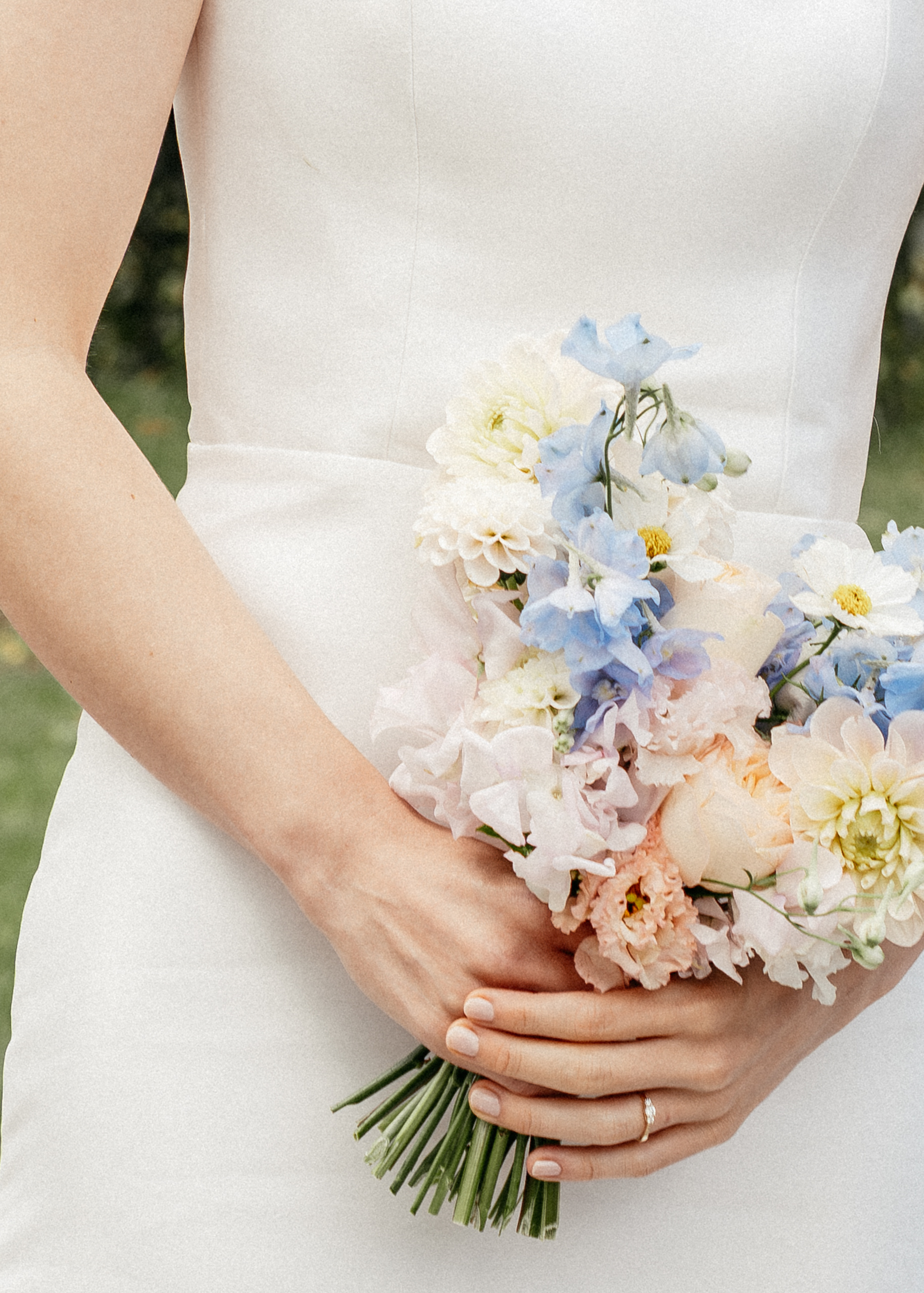 Detailaufnahme einer Braut im weißen Hochzeitskleid, die einen bunten Brautstrauß hält, Hochzeitsfotografie von emilys stories