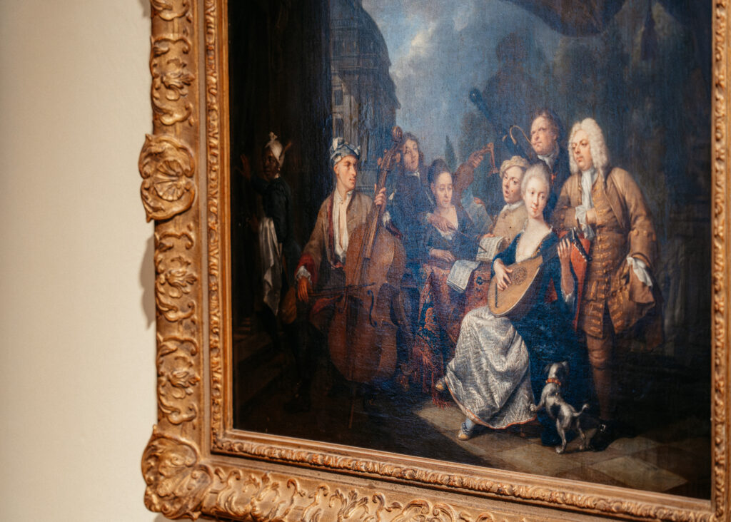 Historisches Ölgemälde in einem verzierten Goldrahmen zeigt musizierende Menschen, Hochzeitsfotografie von emilys stories